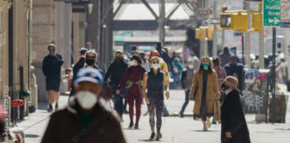 Anonymous crowd of people walking street wearing masks during Covid 19 pandemic in New York City