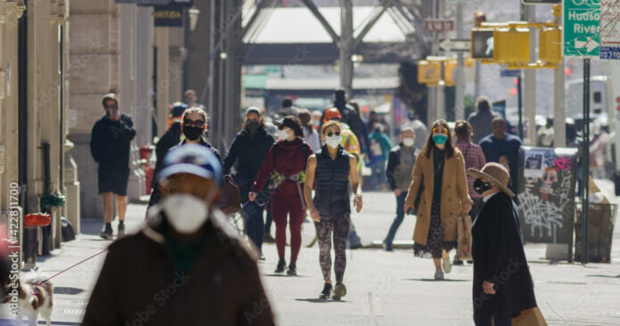 Anonymous crowd of people walking street wearing masks during Covid 19 pandemic in New York City