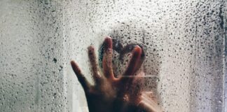 person touching clear shower glass