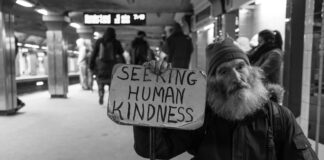 man holding card with seeking human kindness text