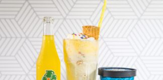 yellow liquid in clear drinking glass beside blue and white labeled bottle