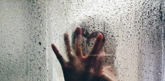 person touching clear shower glass