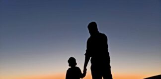 silhouette of man and woman standing on beach during sunset