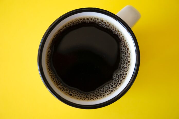 cup of black coffee on yellow surface
