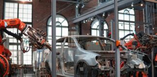gray vehicle being fixed inside factory using robot machines