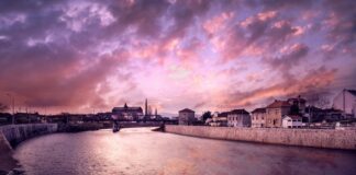 body of water between buildings under blue and gray sky