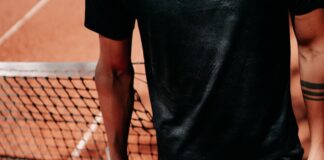 person in black shorts holding green tennis racket