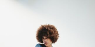 a man sitting on top of a stool wearing a jean jacket