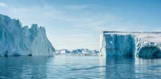 icebergs on body of water under blue and white sky at daytime