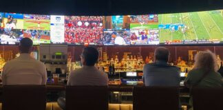 a group of people sitting at a bar watching tv