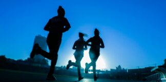 silhouette of three women running on grey concrete road