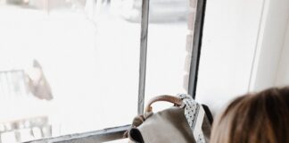 girl wearing grey long-sleeved shirt using MacBook Pro on brown wooden table