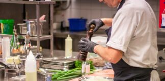 man putting herb on food