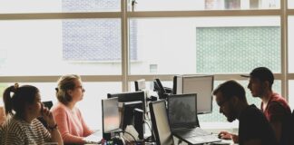 woman in pink shirt sitting in front of black laptop computer