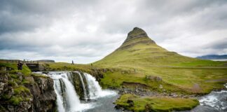 photo of waterfalls beside hill during cloudy daytime