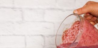 a person pouring a smoothie into a jar
