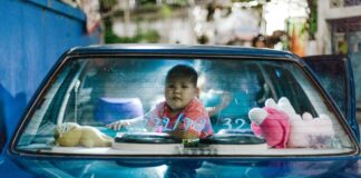 a small child sitting in the back of a blue car