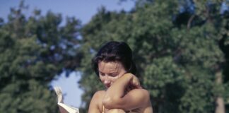 woman sitting on mat reading book