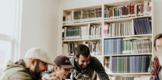 three men laughing while looking in the laptop inside room