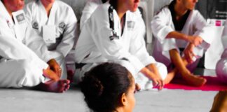 girl wearing karate gi sitting on pink puzzle mat