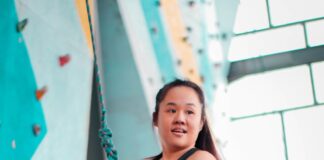 woman in black tank top and black leggings sitting on white concrete wall during daytime