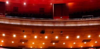 An empty auditorium with red seats and a stage