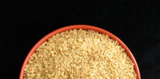 a bowl of sesame seeds on a black background