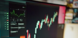 a person writing on a piece of paper next to a computer monitor