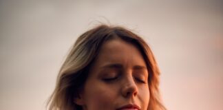 woman in white vest and black bikini with hand on chest