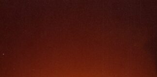 a person standing in front of a large orange moon
