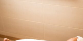 a woman laying on top of a bed with a hair dryer