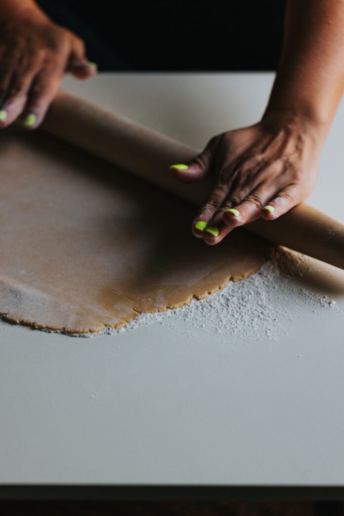 person holding brown wooden rolling pin