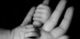 photo of baby holding person's fingers