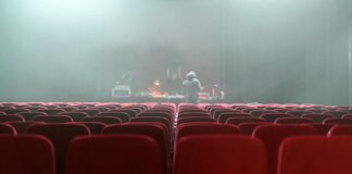 people sitting on red chairs watching a band performing on stage