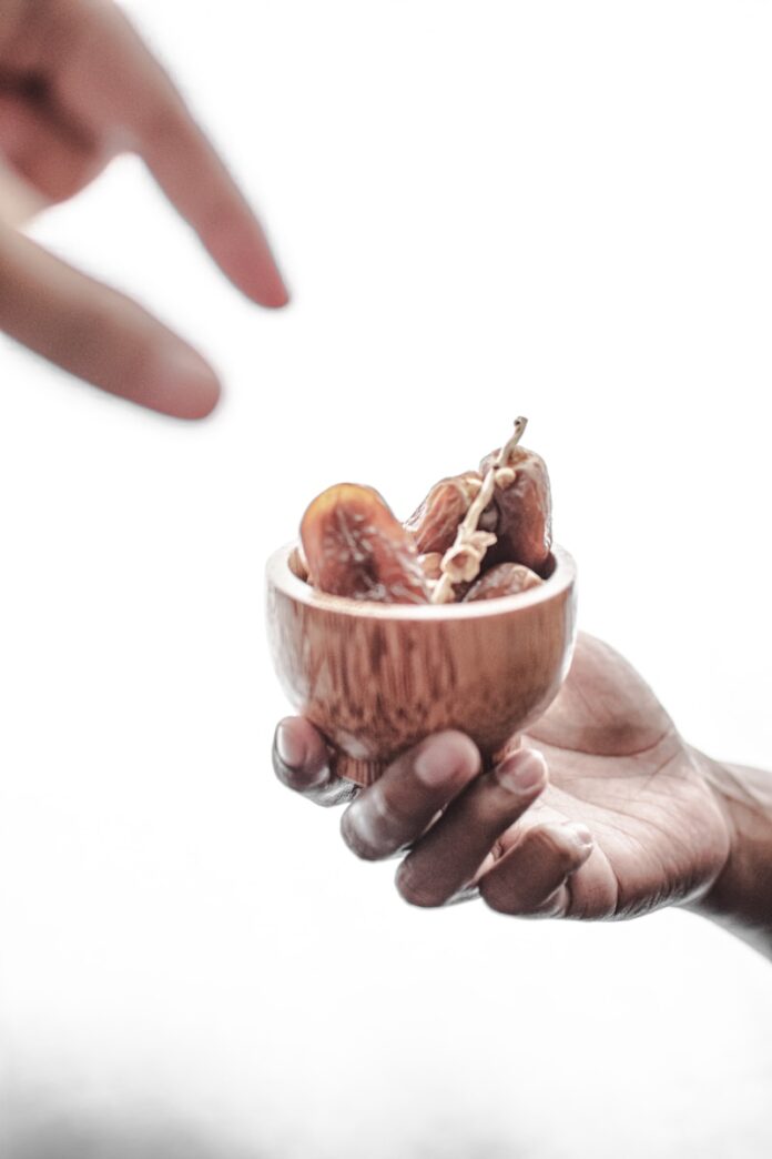 two hands holding a small bowl of food