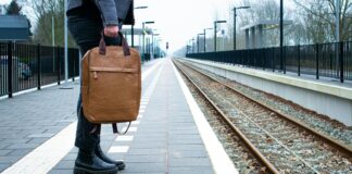 a man carrying a brown briefcase on a train track