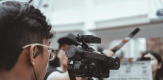 man in black framed eyeglasses holding black video camera