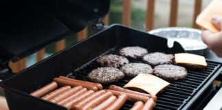person standing in front grill grilling sausage