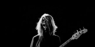man playing electric bass guitar in grayscale photography