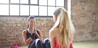 woman sitting on yoga mat with in front of girl during daytime