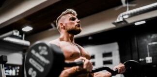 topless man in black shorts carrying black dumbbell