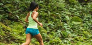 woman in white tank top running on dirt road during daytime