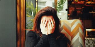 woman in black long sleeve shirt covering her face