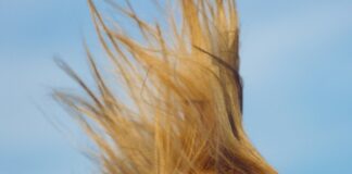 woman wearing yellow halter top whipping hair
