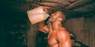 topless man drinking water from plastic container