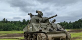a military tank sitting on top of a lush green field