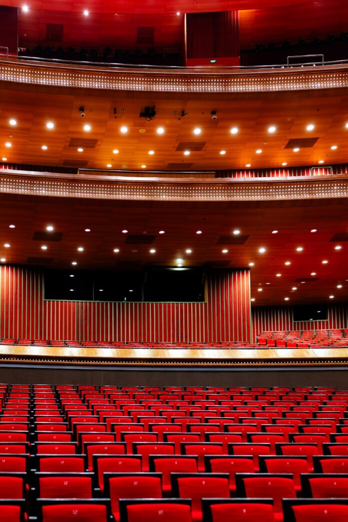 An empty auditorium with red seats and a stage