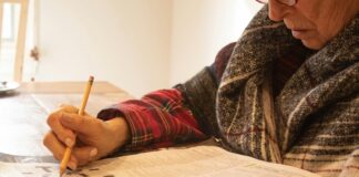 person in black and white sweater writing on white paper