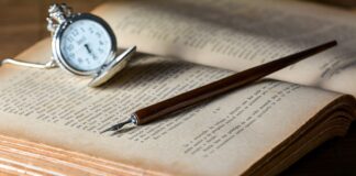 brown pen on top of book beside gray pocket watch