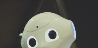 white robot toy holding black tablet
